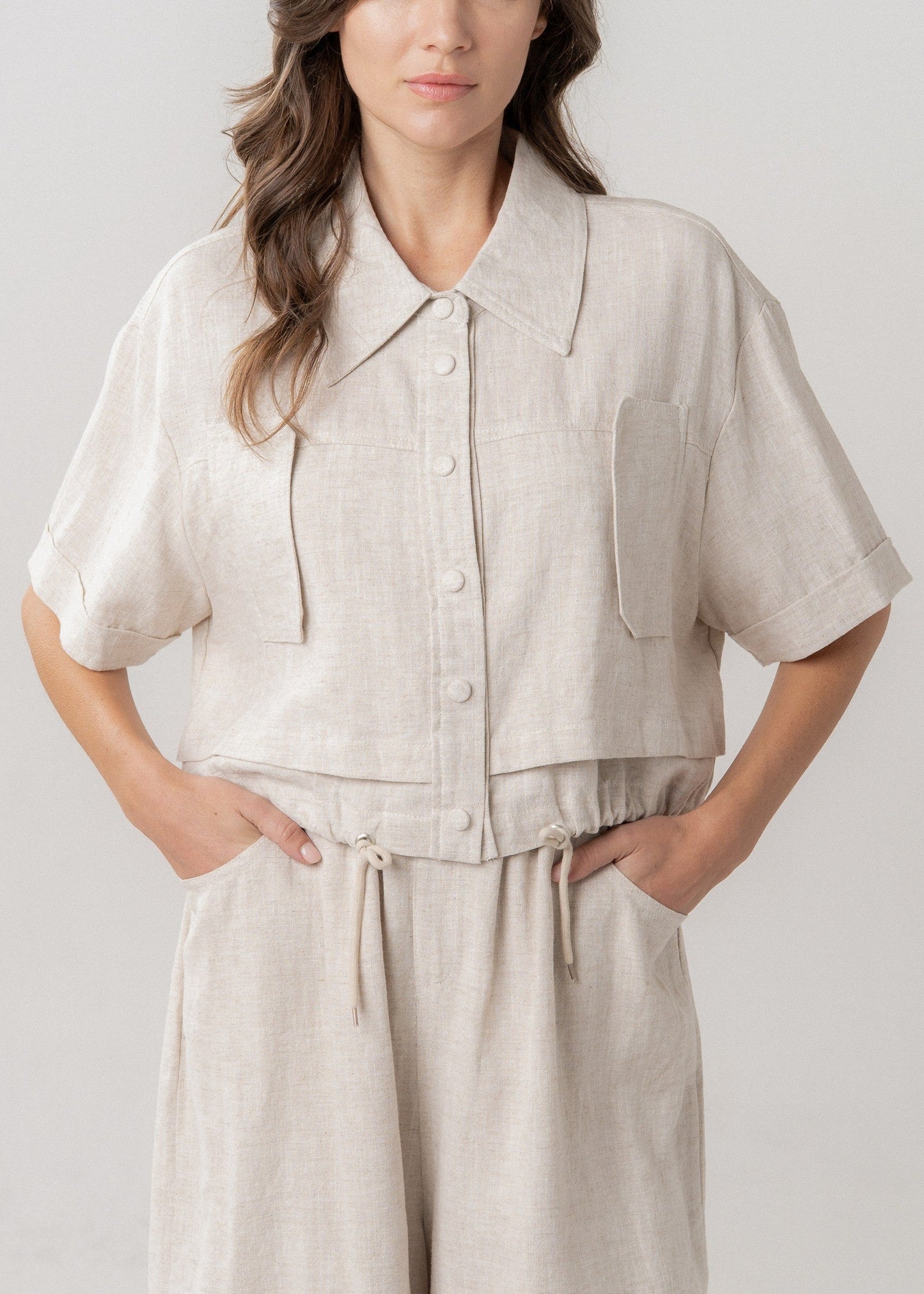 Woman wearing a beige outfit with a plain background
