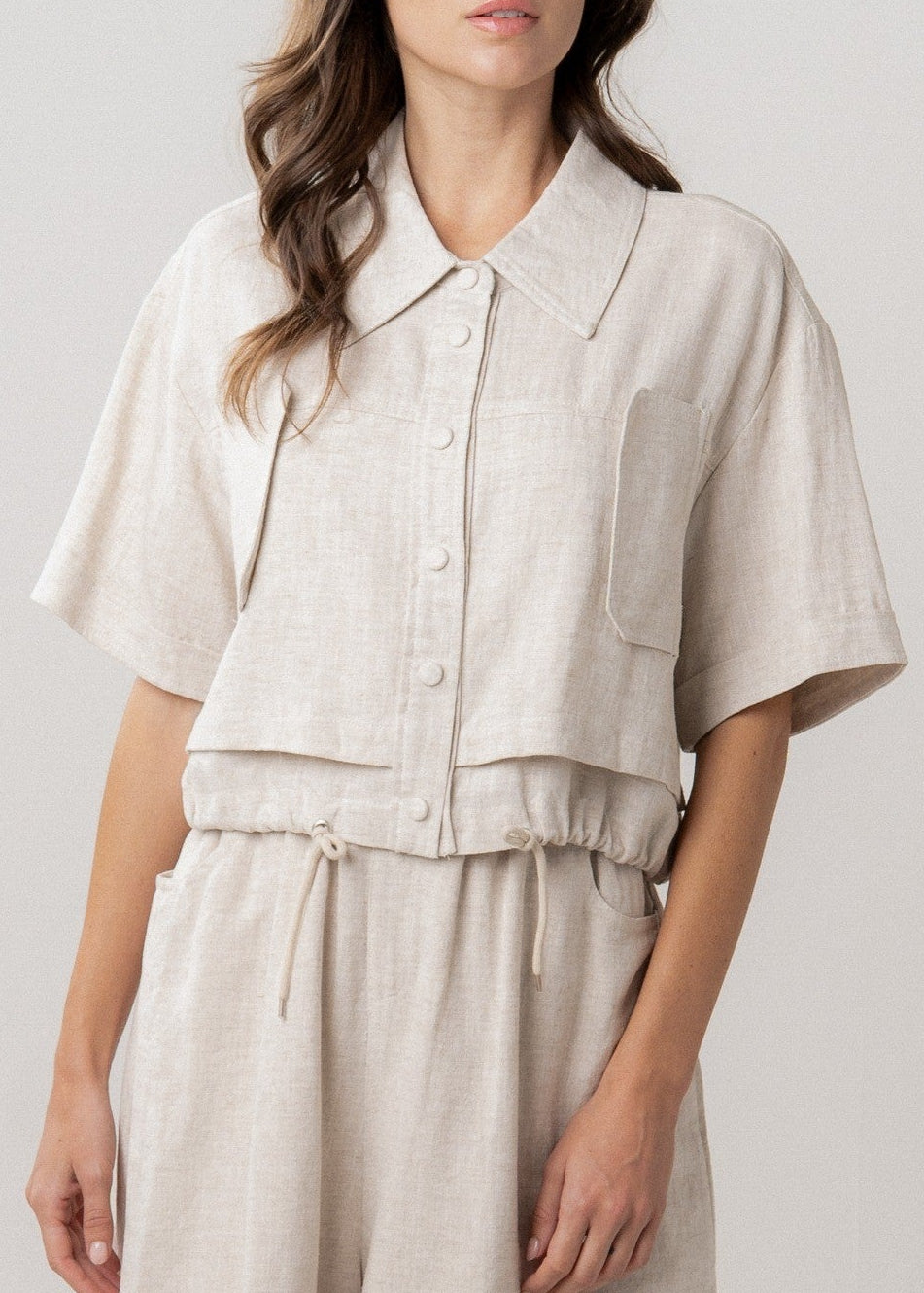 Woman wearing a beige utility crop top on a white background