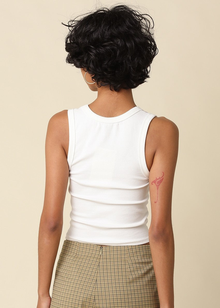Person wearing a white sleeveless top and plaid pants on a beige background