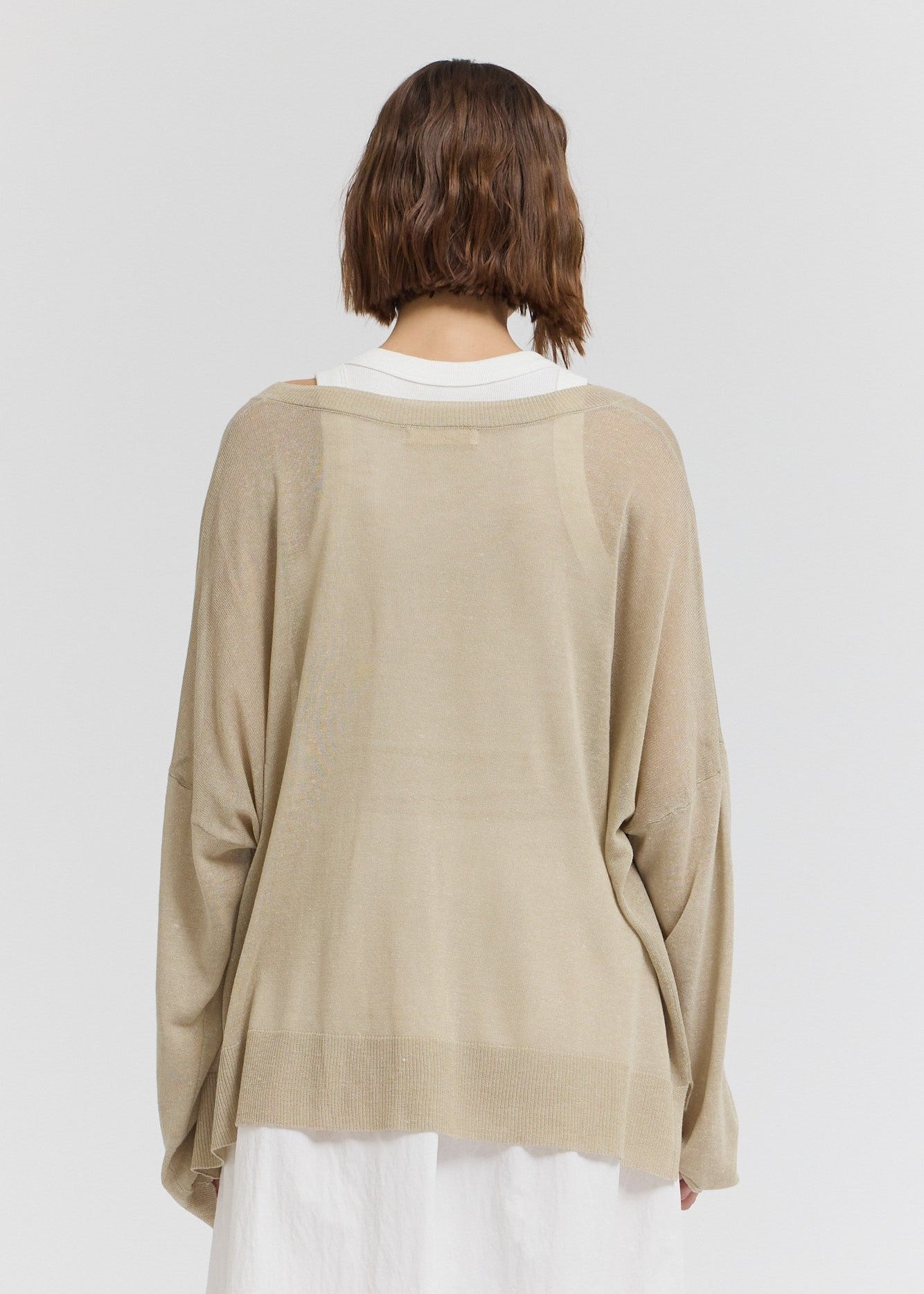 Beige oversized knit top with white ribbed crew neckline, shown from back view.