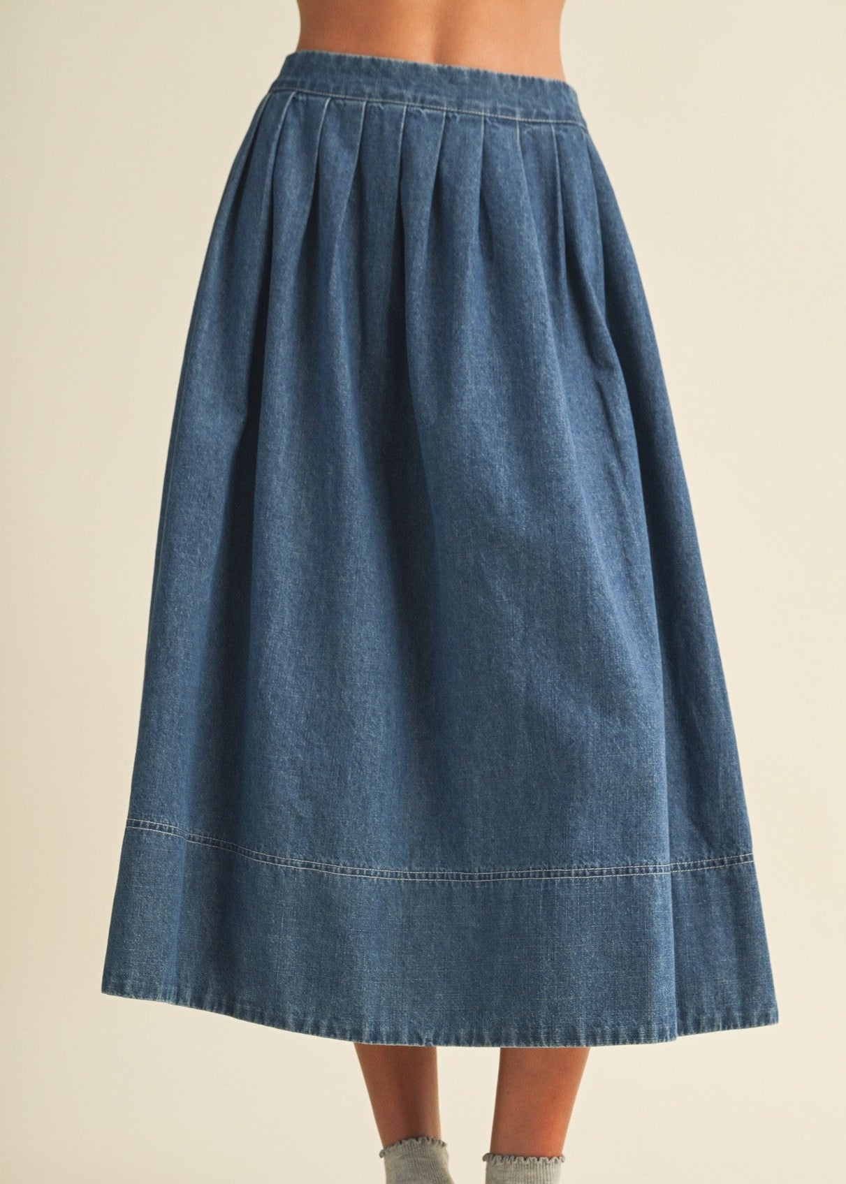 Blue denim skirt with pleated waistband and mid-calf A-line silhouette.