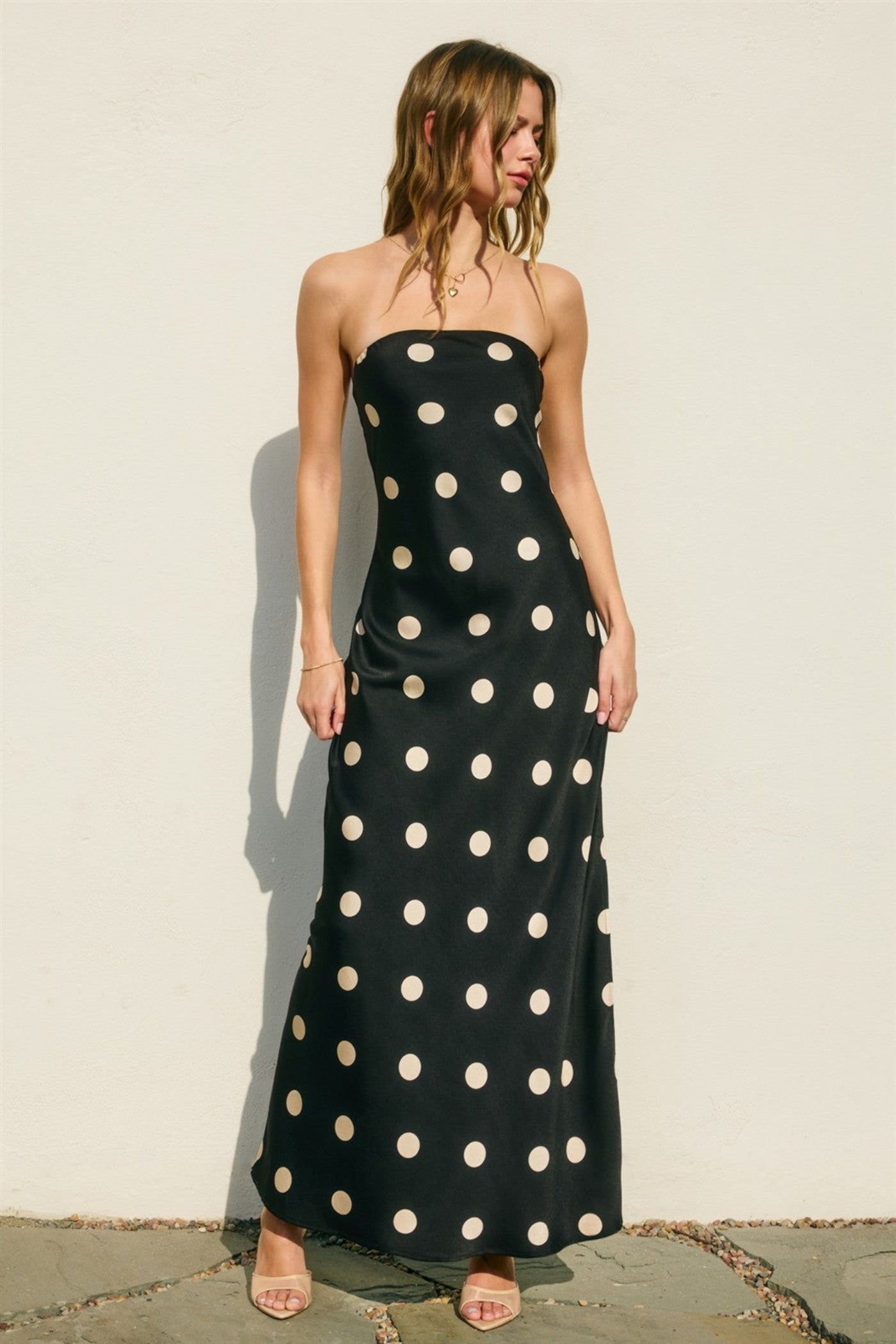 Woman wearing a black dress with white polka dots against a plain background