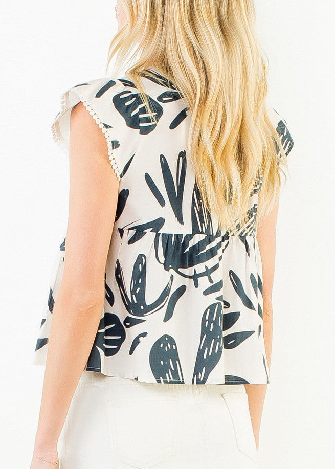 A woman shown from the back wearing a sleeveless top with a black tropical leaf print on a cream background, paired with a cream mini skirt, against a plain white studio background.