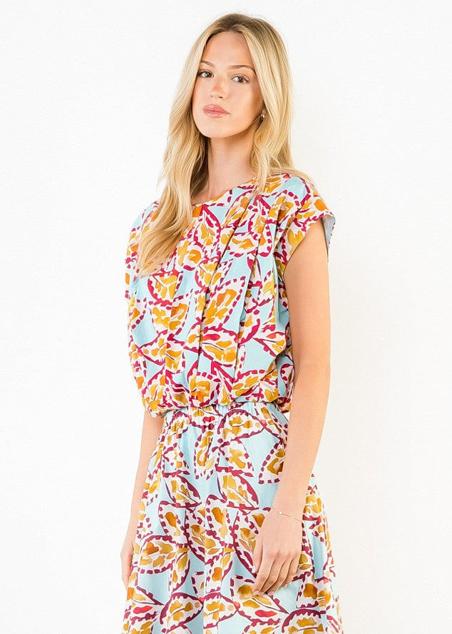 Sleeveless crop top with multicolored abstract print in yellow, pink, and blue on light background.