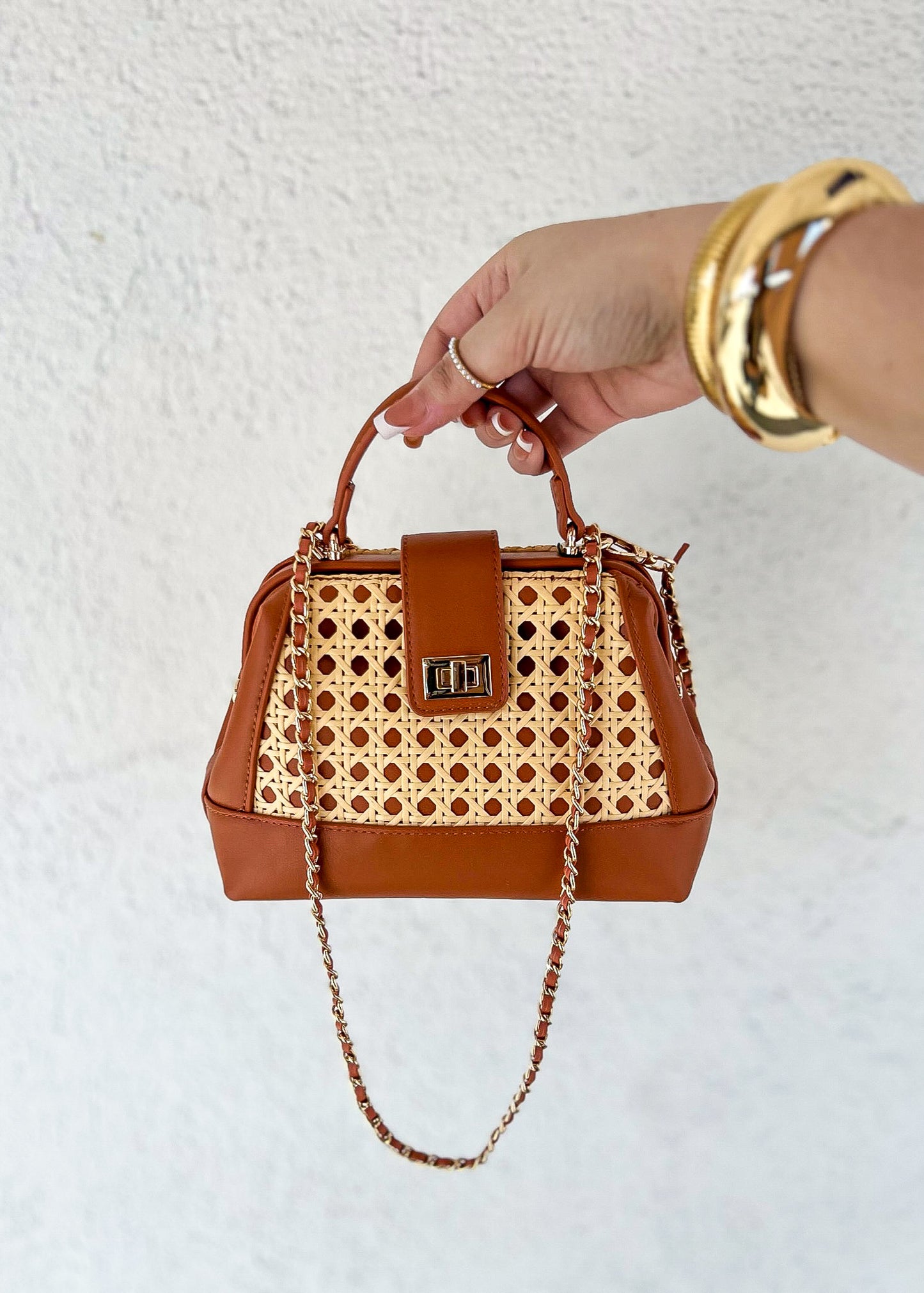 Cognac leather handbag with woven lattice panel, dual handles, chain strap, and gold-tone hardware.
