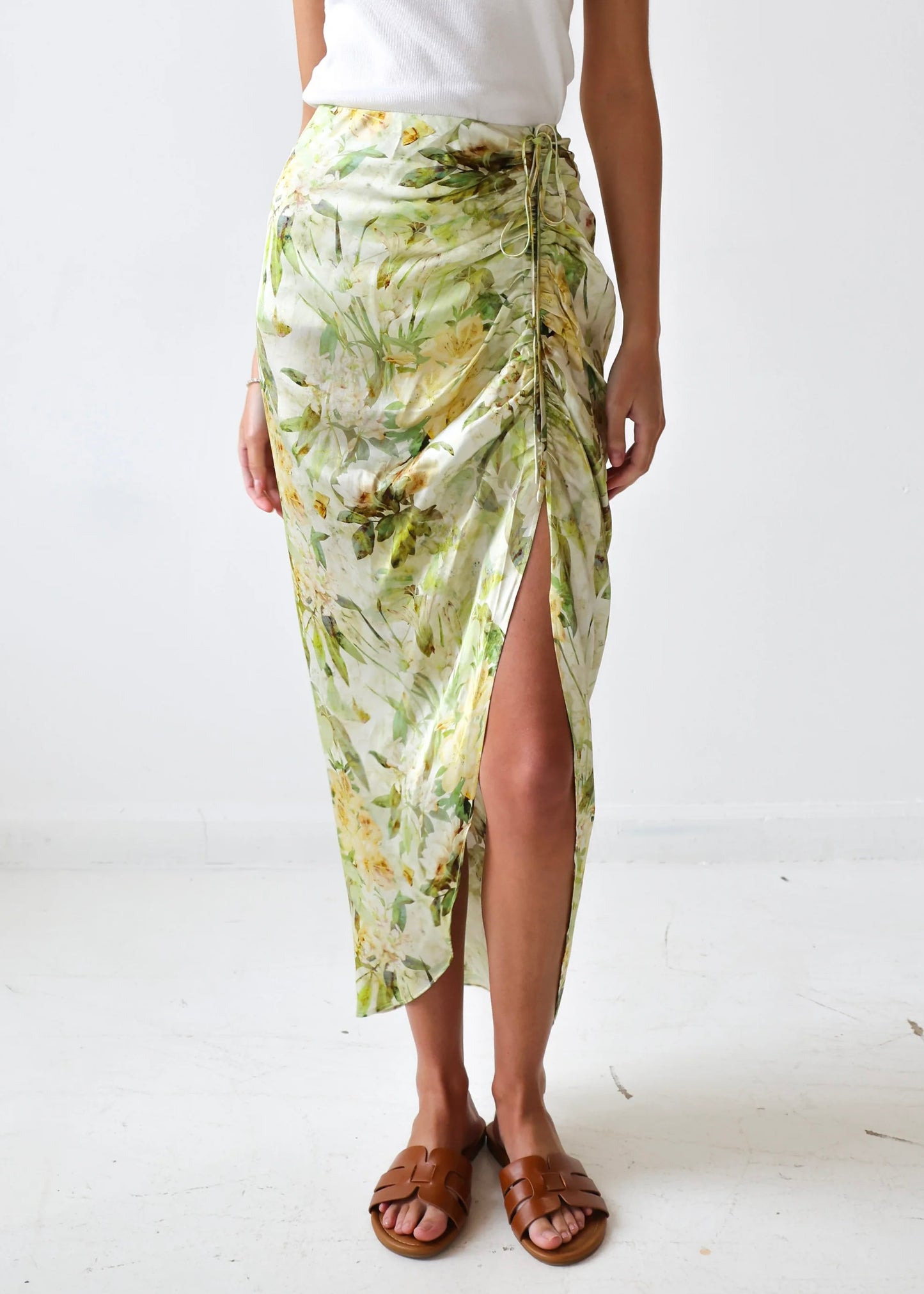 Cream wrap skirt with green and yellow floral print, featuring a side slit and drawstring closure.