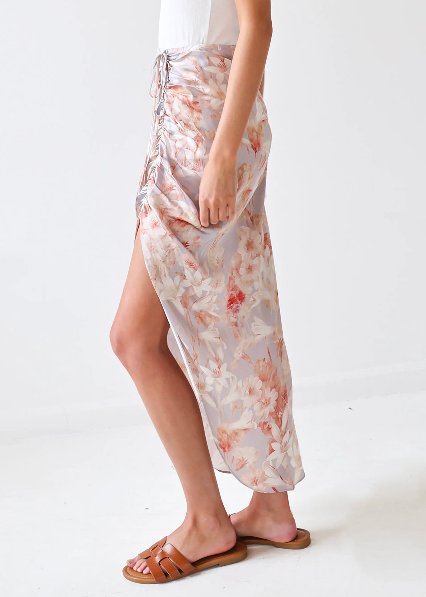 Floral wrap skirt in cream and coral tones with side lace-up closure, worn with brown leather sandals.