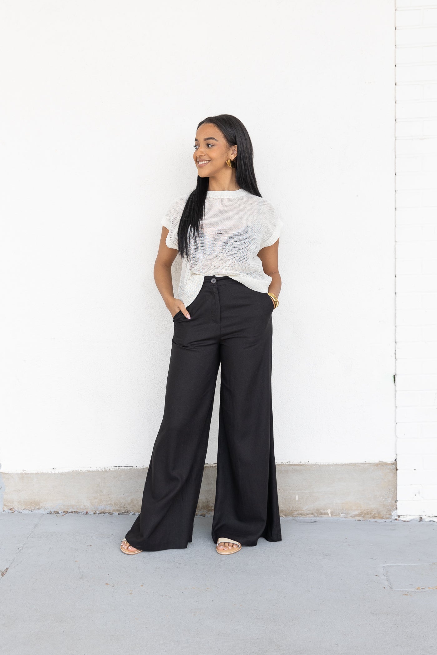 Black wide-leg pants with front pockets and button waist, styled with white t-shirt.