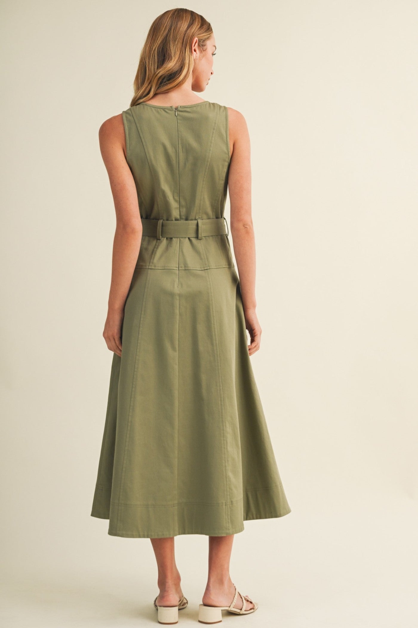 Woman wearing a green dress with a belt on a beige background