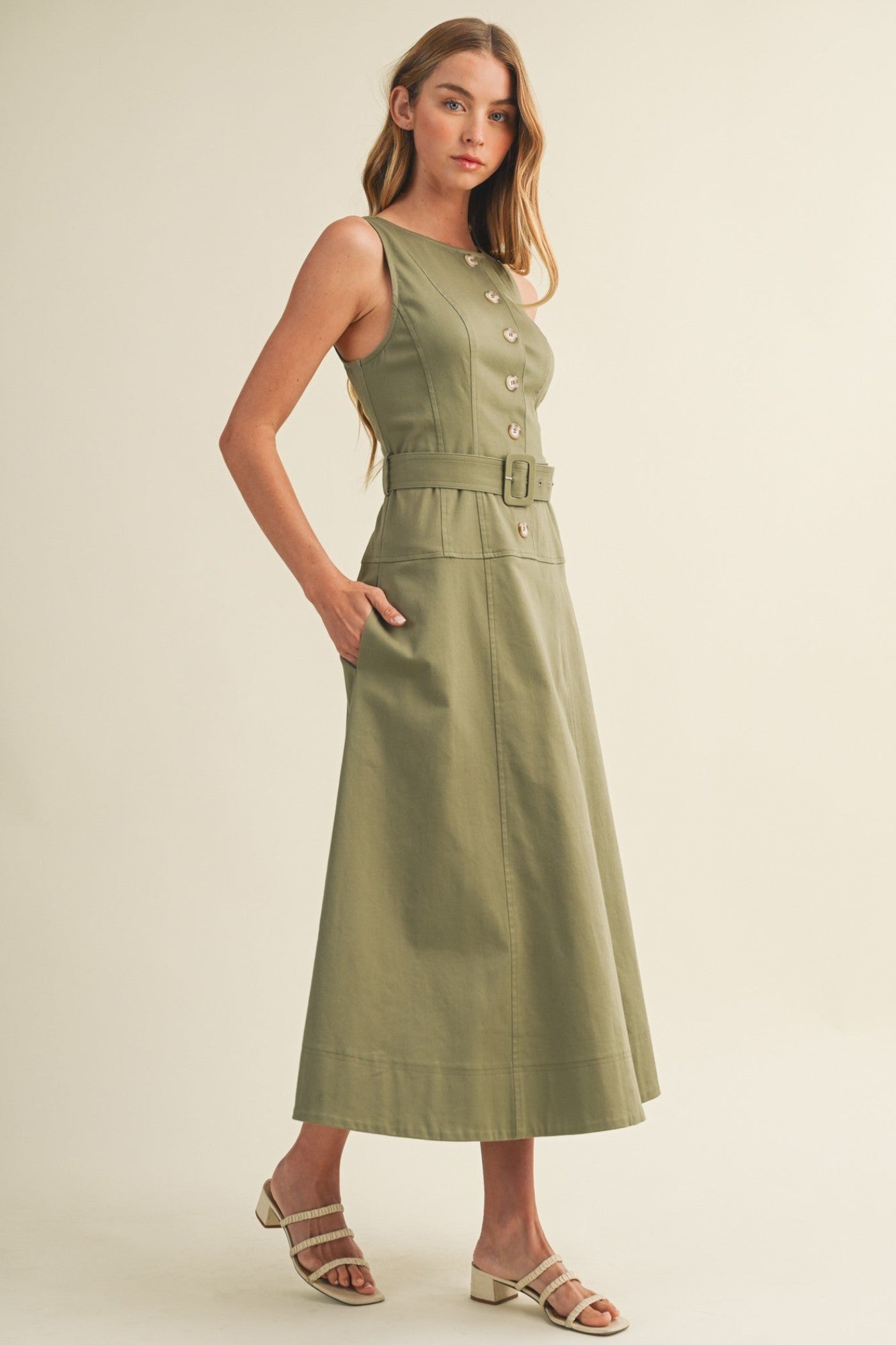 Woman wearing a green dress with a belt on a beige background
